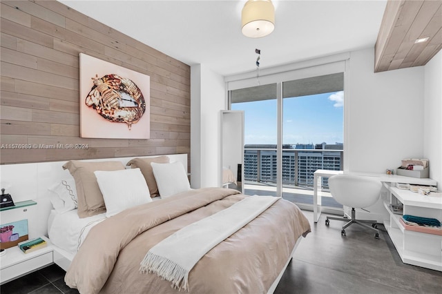 bedroom with wood walls, access to outside, and a wall of windows