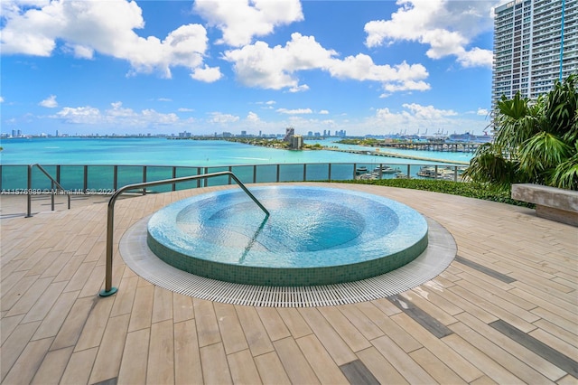 view of swimming pool featuring a water view and an in ground hot tub