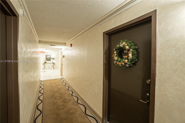 hallway featuring carpet flooring, crown molding, and a textured ceiling