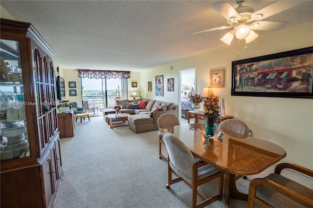 carpeted dining room featuring a textured ceiling and ceiling fan