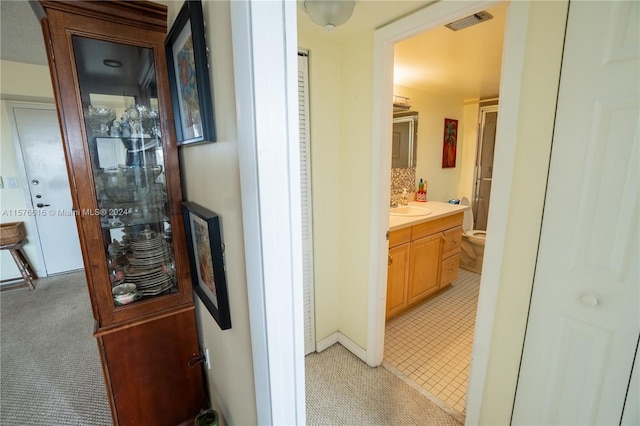 hall featuring light colored carpet and sink