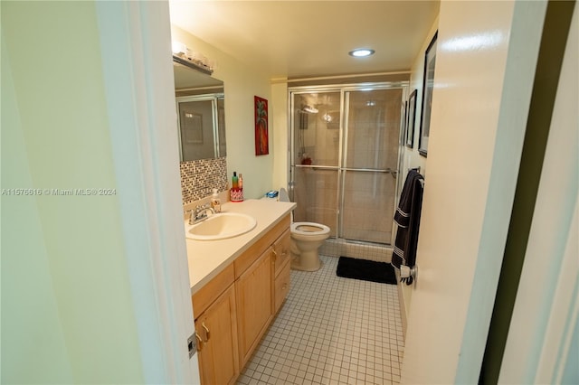 bathroom with walk in shower, vanity, tile floors, and toilet