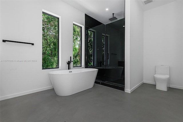 bathroom with a washtub, toilet, and concrete floors