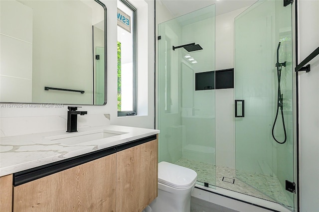 bathroom with toilet, large vanity, and a shower with shower door