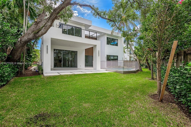 back of house featuring a balcony and a lawn