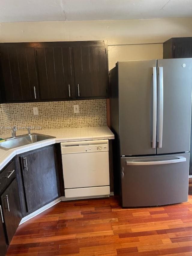 kitchen with sink, tasteful backsplash, light hardwood / wood-style floors, dishwasher, and stainless steel fridge