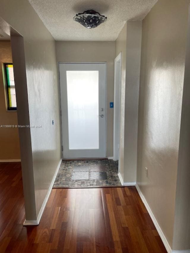 doorway to outside featuring dark hardwood / wood-style flooring and a textured ceiling