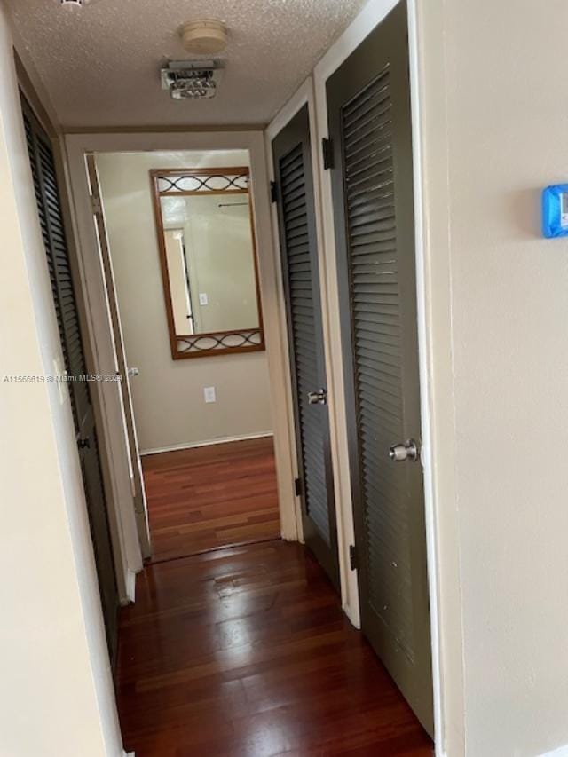 hall with hardwood / wood-style flooring and a textured ceiling