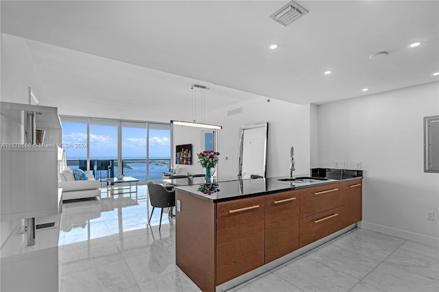 kitchen with pendant lighting, expansive windows, a water view, sink, and light tile floors