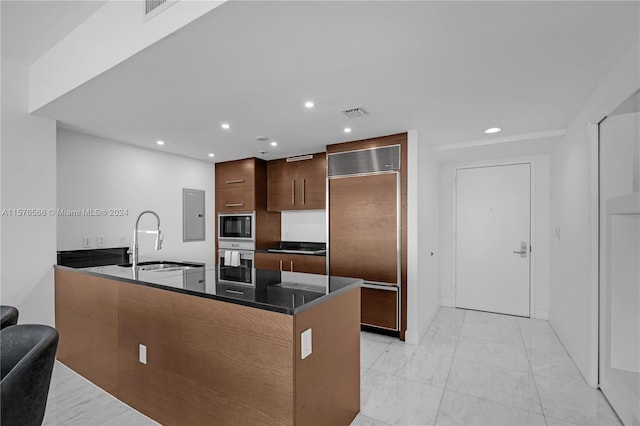 kitchen with sink, kitchen peninsula, light tile floors, and built in appliances