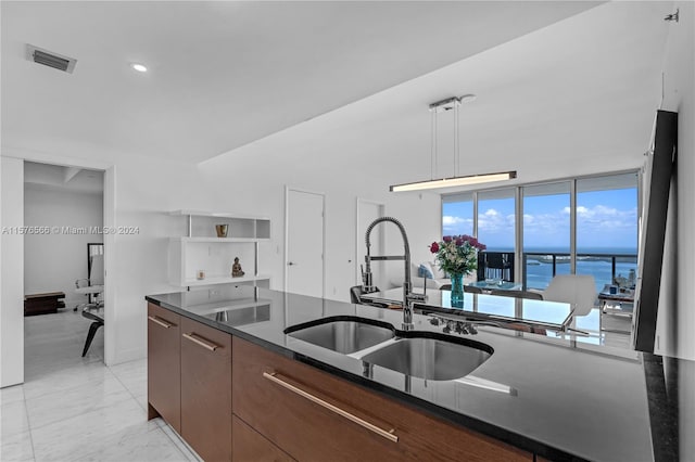 kitchen featuring a water view, hanging light fixtures, sink, and light tile flooring