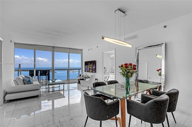 tiled dining room with expansive windows and a water view