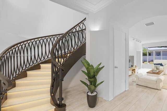 stairs featuring hardwood / wood-style flooring and ornamental molding