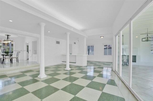 unfurnished room featuring decorative columns and brick wall