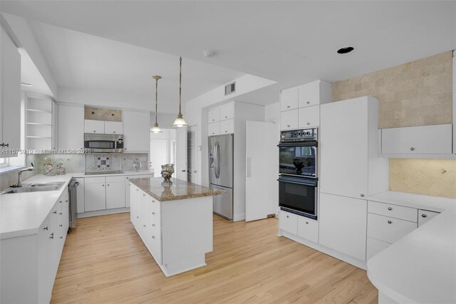 kitchen with white cabinets, black appliances, a kitchen island, sink, and hanging light fixtures