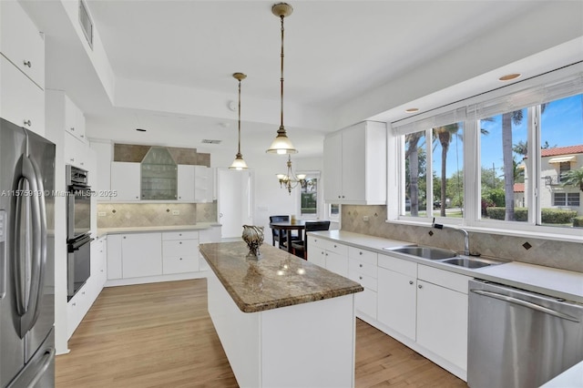 kitchen featuring sink, white cabinets, a kitchen island, decorative backsplash, and stainless steel appliances