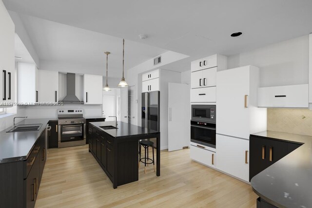 kitchen featuring sink, a kitchen island, a breakfast bar area, stainless steel appliances, and wall chimney exhaust hood