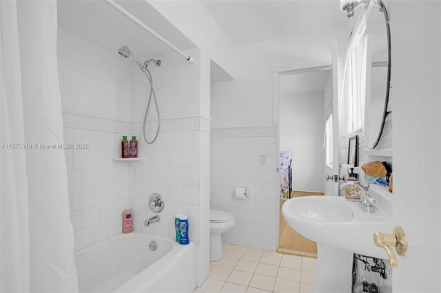 bathroom with tile walls, tile patterned floors, tiled shower / bath combo, and toilet