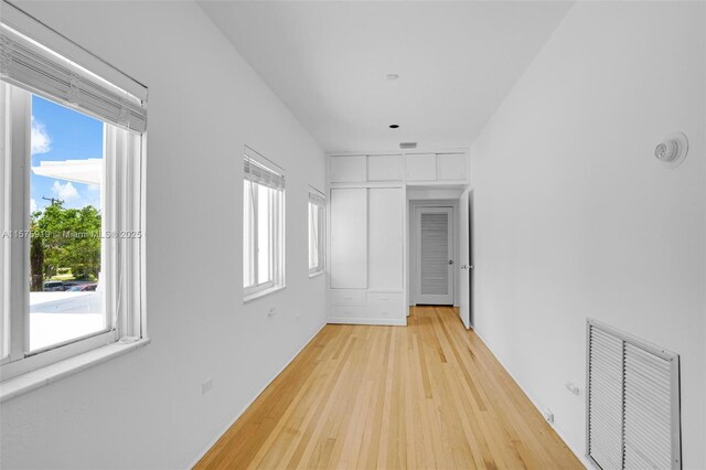 hall with a healthy amount of sunlight and light hardwood / wood-style floors