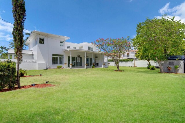 rear view of house featuring a lawn and ceiling fan