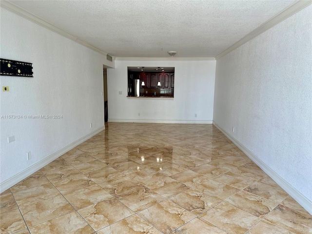 tiled empty room featuring ornamental molding and a textured ceiling