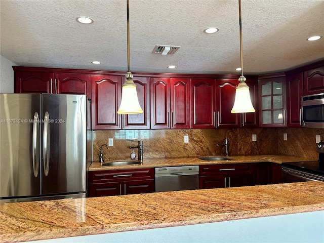 kitchen featuring appliances with stainless steel finishes, sink, hanging light fixtures, and backsplash