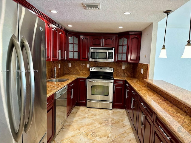 kitchen featuring decorative light fixtures, appliances with stainless steel finishes, sink, and backsplash