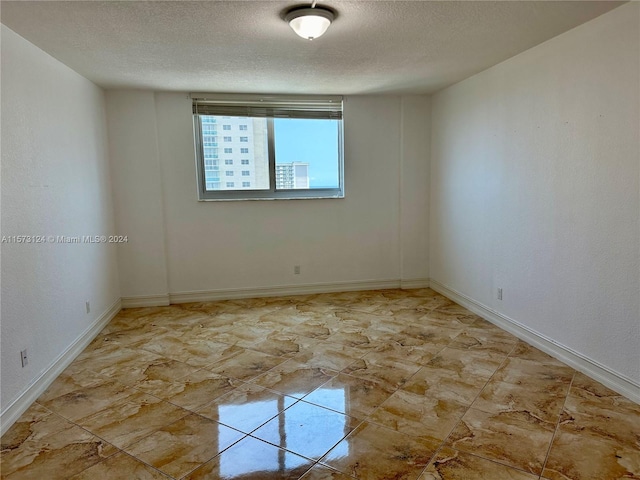 spare room featuring tile floors and a textured ceiling