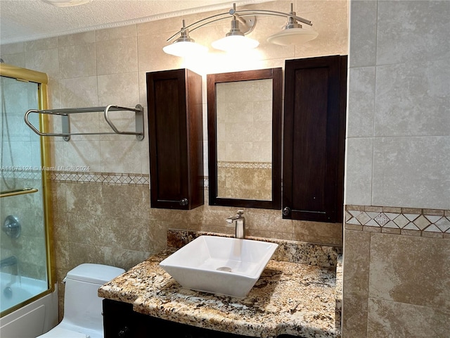 full bathroom featuring tile walls, toilet, a textured ceiling, and vanity