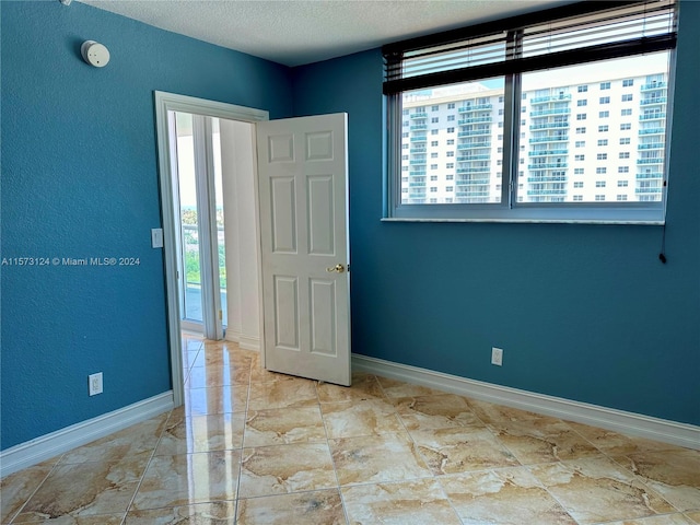 tiled spare room featuring a textured ceiling