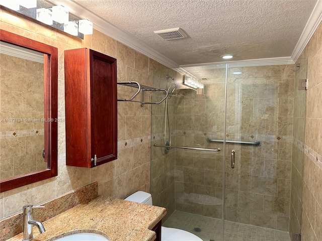 bathroom featuring tile walls, toilet, a shower with door, vanity, and a textured ceiling