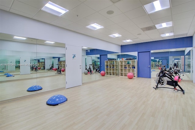 exercise room with light hardwood / wood-style floors and a drop ceiling