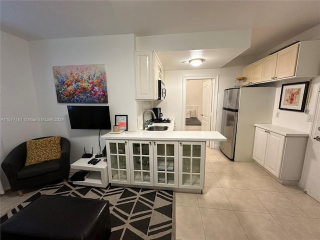 kitchen featuring appliances with stainless steel finishes, white cabinets, kitchen peninsula, sink, and light tile flooring