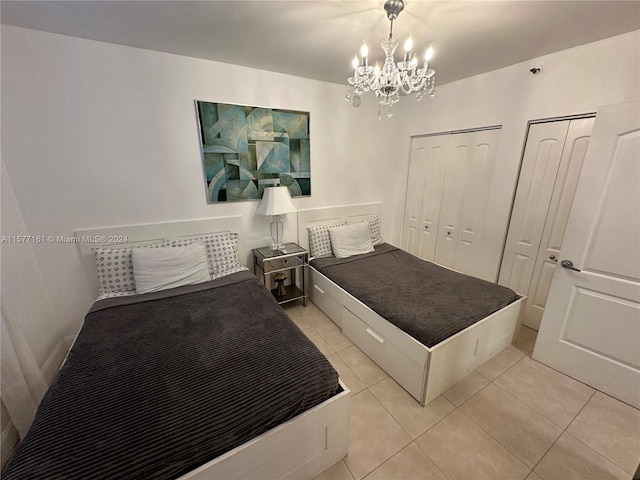 bedroom with a notable chandelier, two closets, and light tile floors