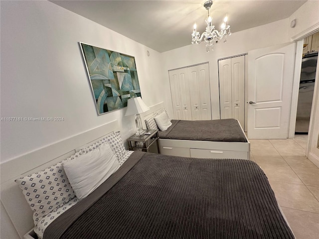 bedroom featuring multiple closets, a chandelier, and light tile floors