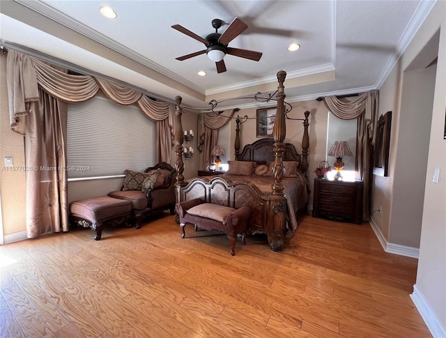 bedroom featuring hardwood / wood-style floors, ceiling fan, ornamental molding, and a tray ceiling