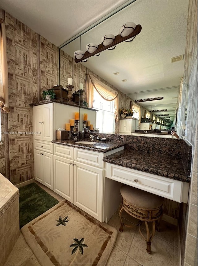 kitchen with a textured ceiling, sink, light tile floors, and white cabinetry