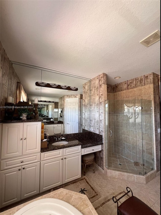 bathroom featuring tile flooring, vanity, a shower with door, and a textured ceiling