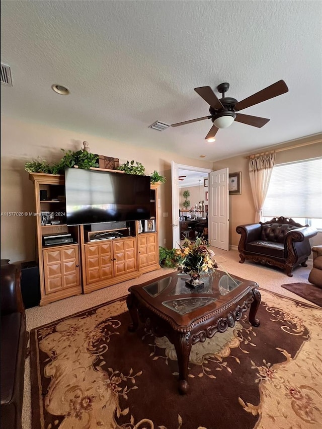 living room featuring light colored carpet, ceiling fan, and a textured ceiling