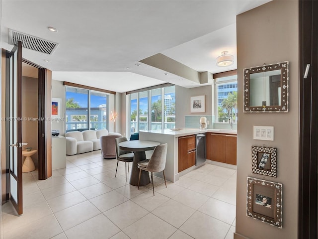 kitchen with dishwashing machine, light tile patterned floors, expansive windows, and kitchen peninsula