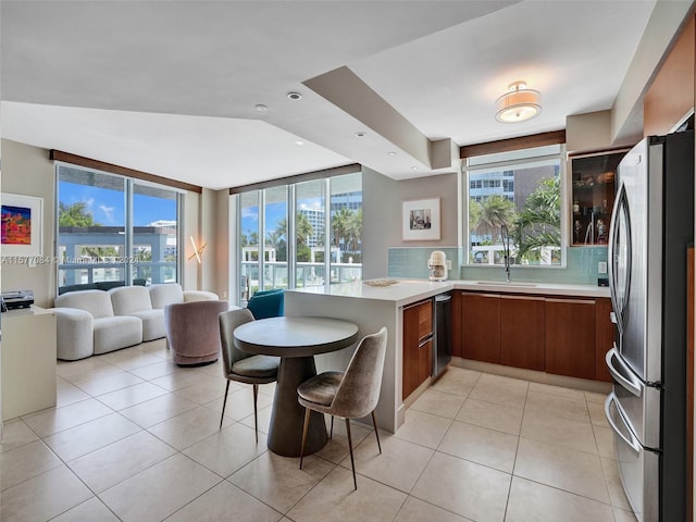 kitchen featuring kitchen peninsula, stainless steel appliances, a wealth of natural light, and light tile patterned floors