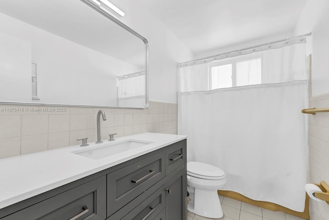 bathroom with tile patterned flooring, vanity, toilet, and tile walls