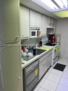 kitchen with white cabinets, white appliances, and light tile floors