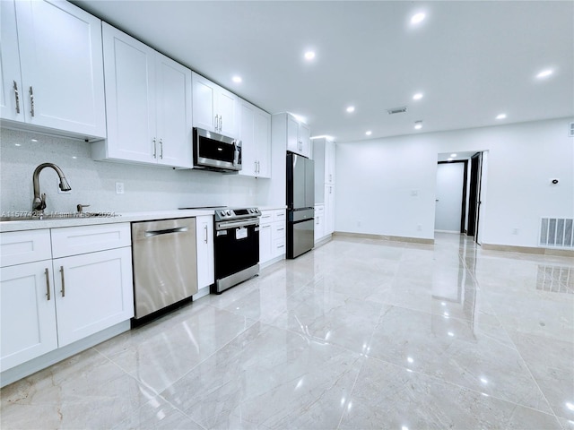 kitchen with light tile flooring, white cabinetry, stainless steel appliances, sink, and tasteful backsplash