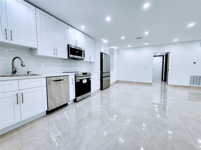 kitchen with light tile flooring, white cabinetry, appliances with stainless steel finishes, sink, and tasteful backsplash