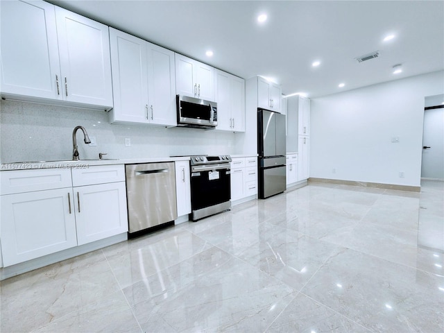 kitchen featuring white cabinets, stainless steel appliances, light tile floors, sink, and tasteful backsplash