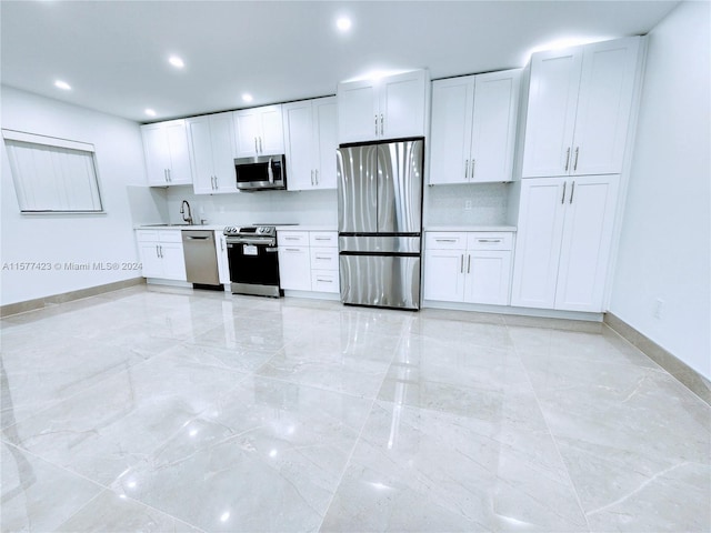 kitchen featuring appliances with stainless steel finishes, sink, light tile floors, and white cabinets