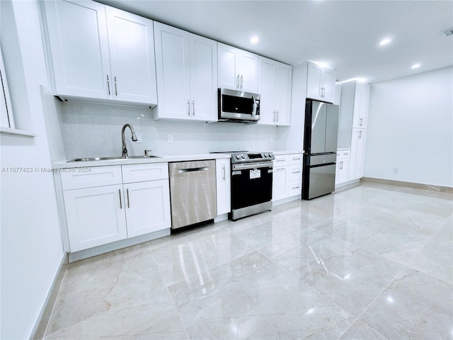 kitchen with appliances with stainless steel finishes, light tile flooring, and white cabinetry