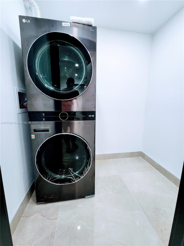 laundry area with tile floors, stacked washing maching and dryer, and hookup for a washing machine