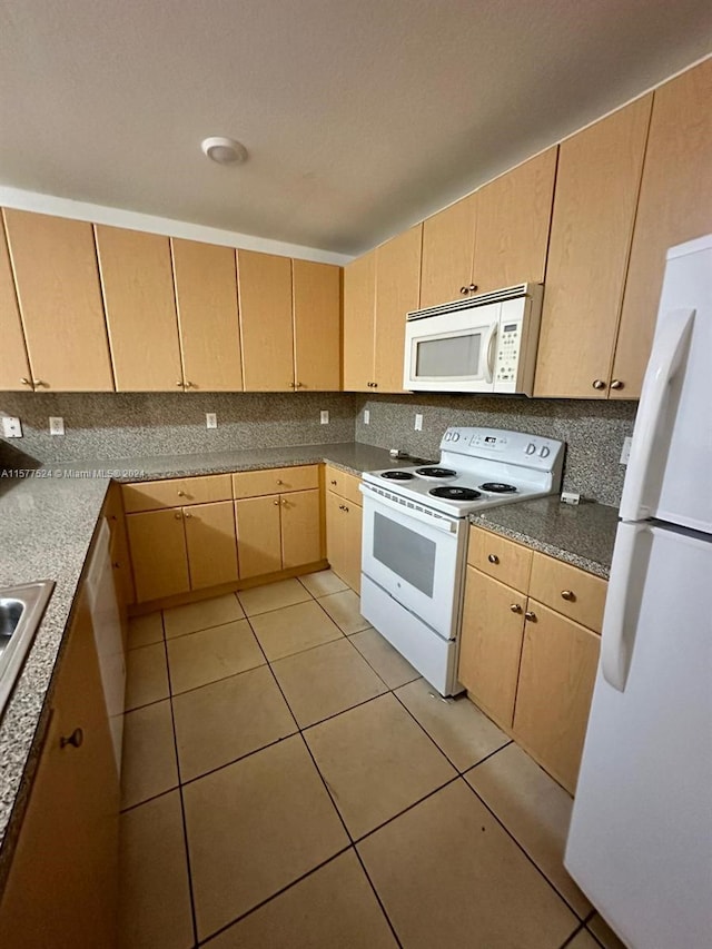 kitchen with light tile patterned flooring, white appliances, and light brown cabinetry